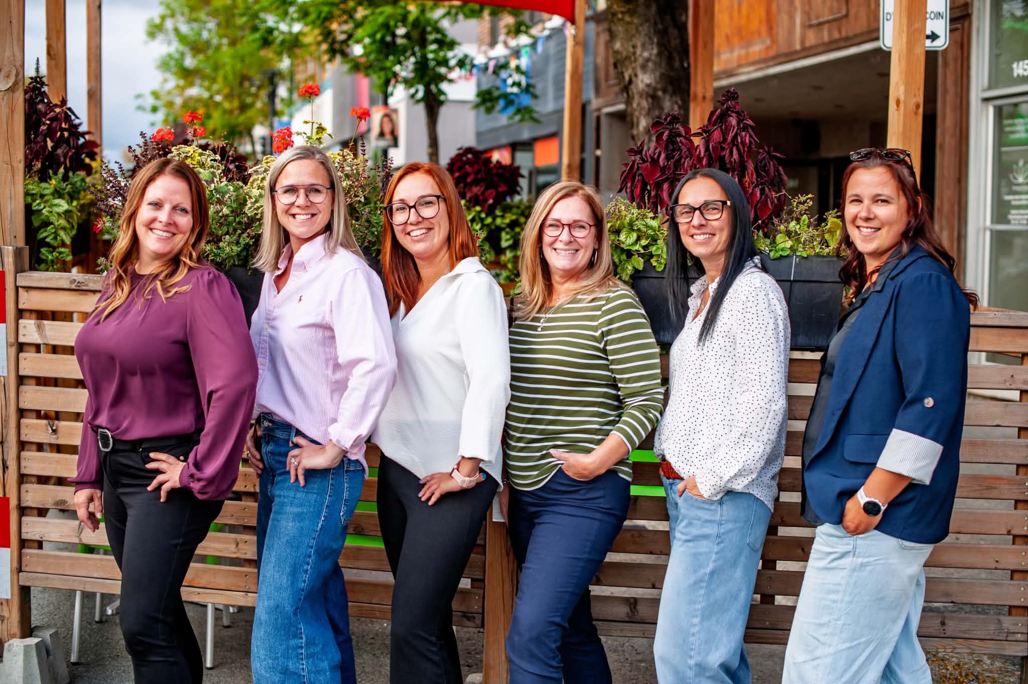 Comité organisateur du Salon de la femme de Rouyn-Noranda, six femmes souriantes devant une terrasse fleurie